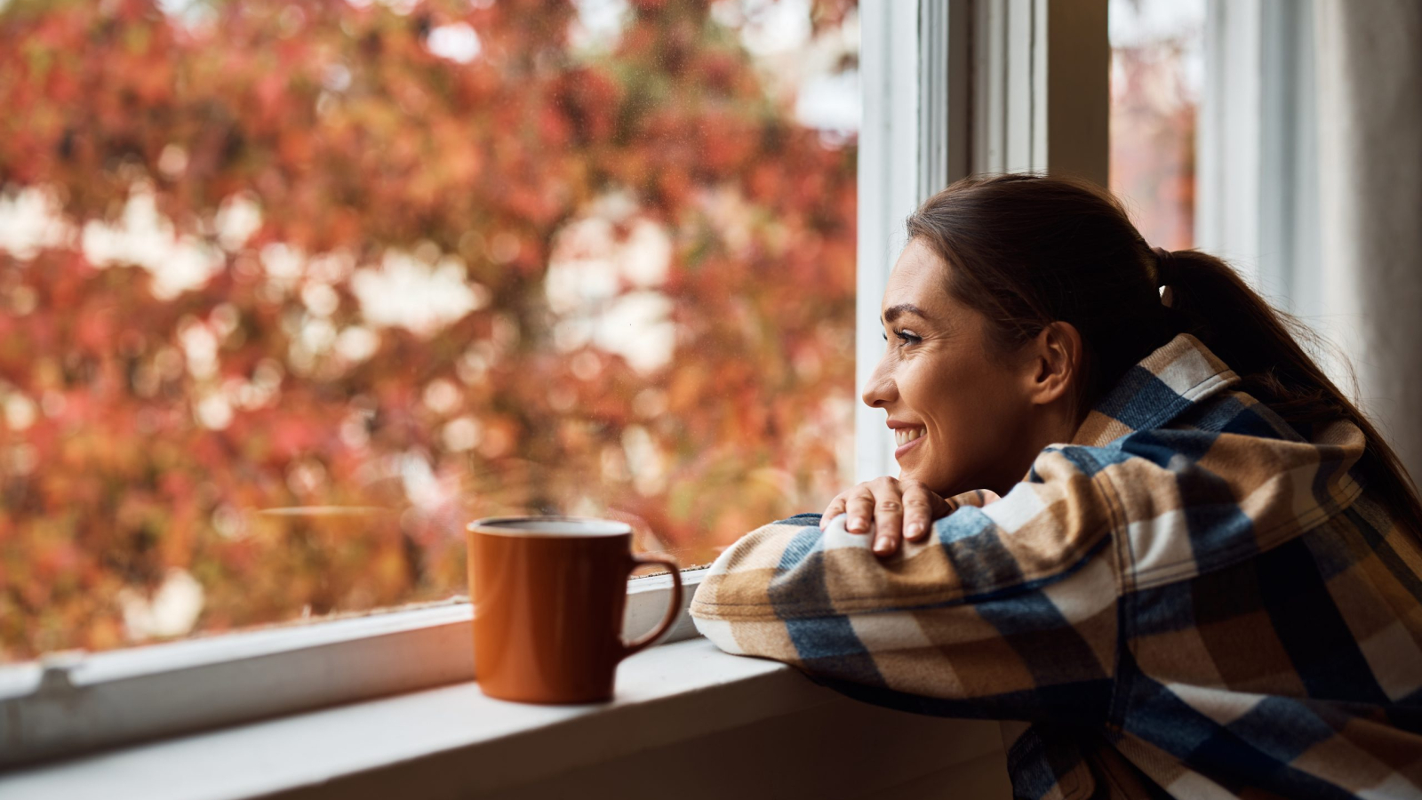Young happy woman enjoying the view from her apartment window. Copy space.